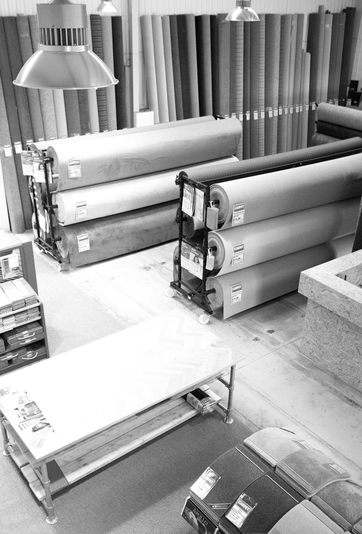 Carpet rolls on racks under industrial lamps in the warehouse